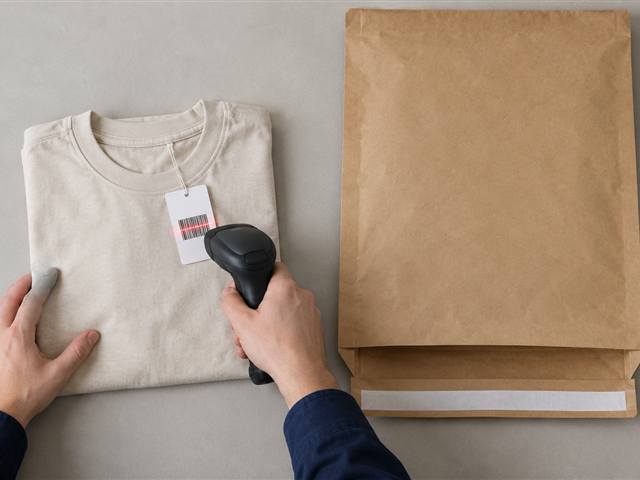 A folded shirt being scanned beside its mailer